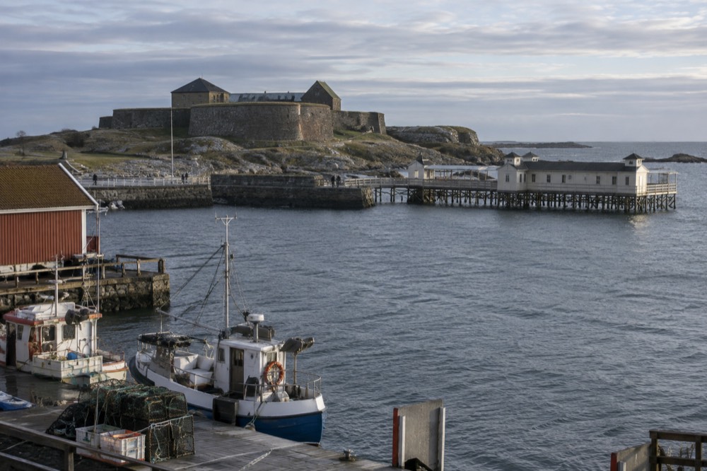 Fishing boats moored in Varberg harbour with wooden buildings behind