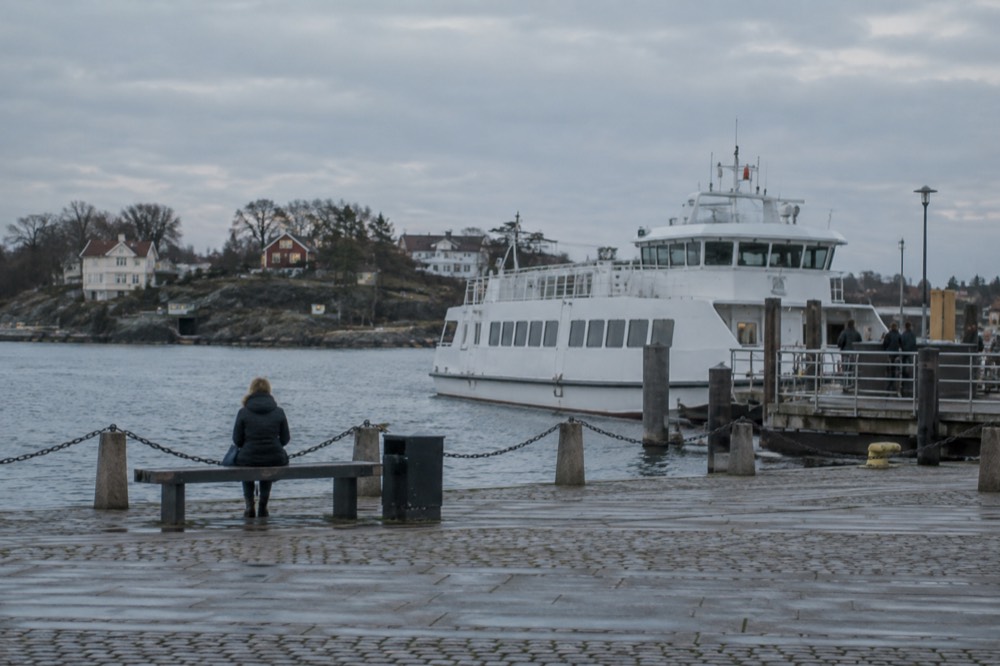 A white archipelago ferry moored at a wooden jetty with a small island village behind it