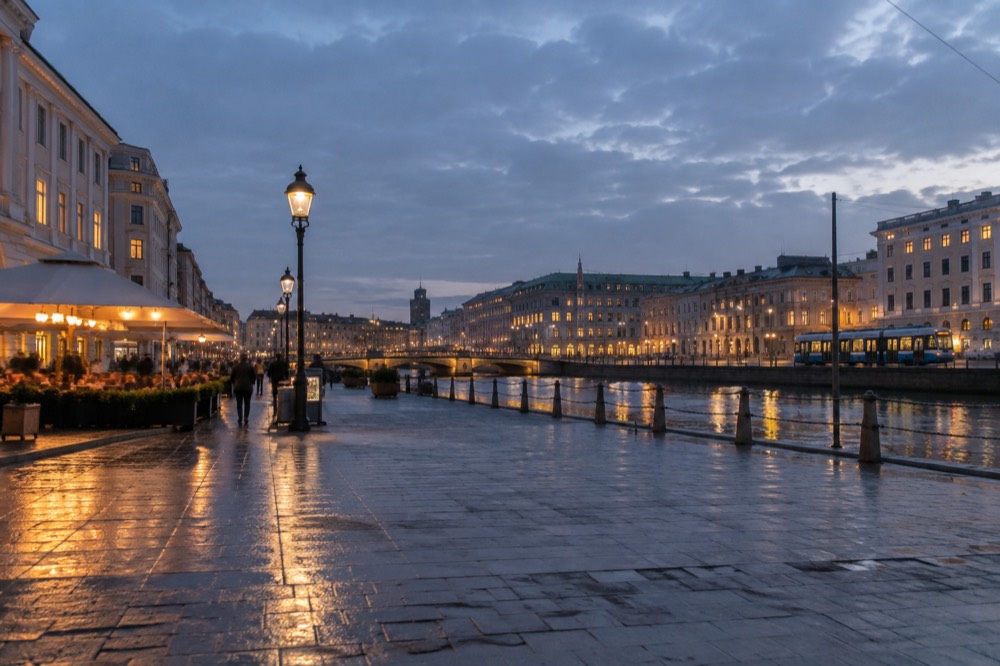 Evening view of a Gothenburg street with restaurant lights reflected on wet cobblestones