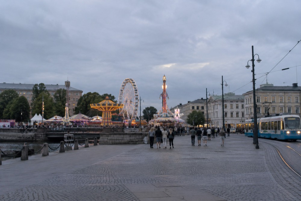 Lit amusement park rides and crowds at a Scandinavian summer funfair
