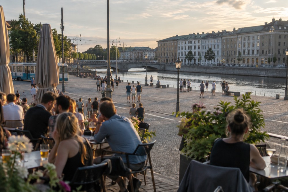 People drinking at outdoor tables on a Gothenburg street in summer evening light
