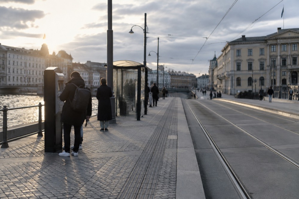 A traveller checking a phone at a tram platform ticket machine