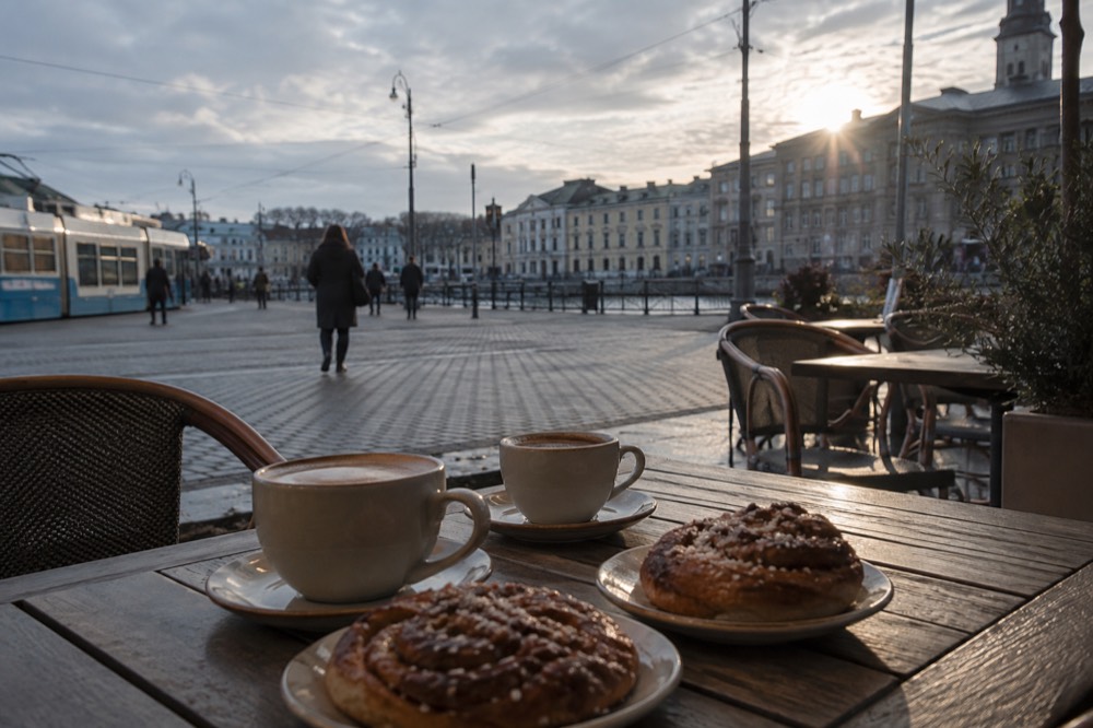 Two coffee cups and cinnamon buns on a wooden cafe table in Gothenburg