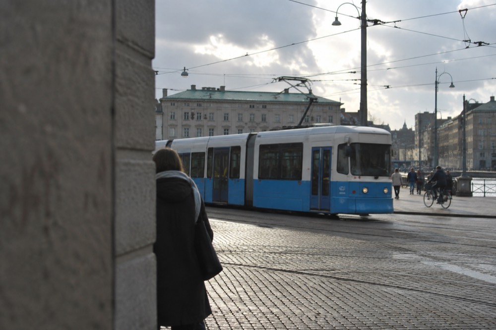 A tram crossing a cobbled junction in central Gothenburg under overhead wires
