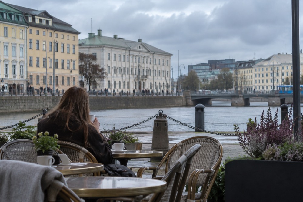 A visitor pausing at an outdoor cafe table in Gothenburg on a bright grey afternoon