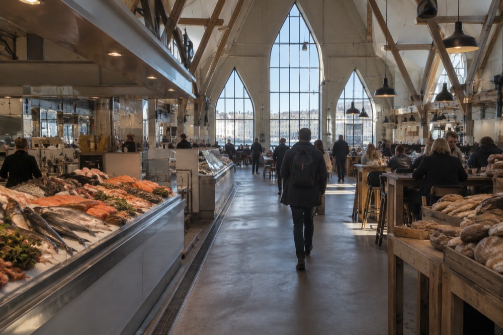 Interior of a food hall with wooden beams, counters and people eating at tables