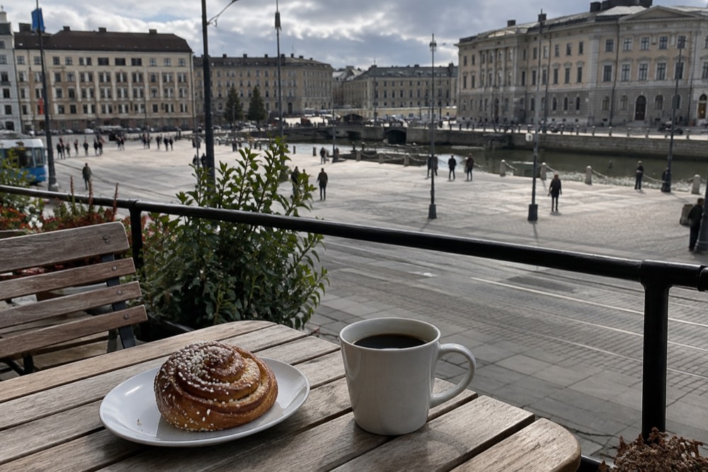 A cinnamon bun and a cup of coffee on a wooden cafe table in Gothenburg