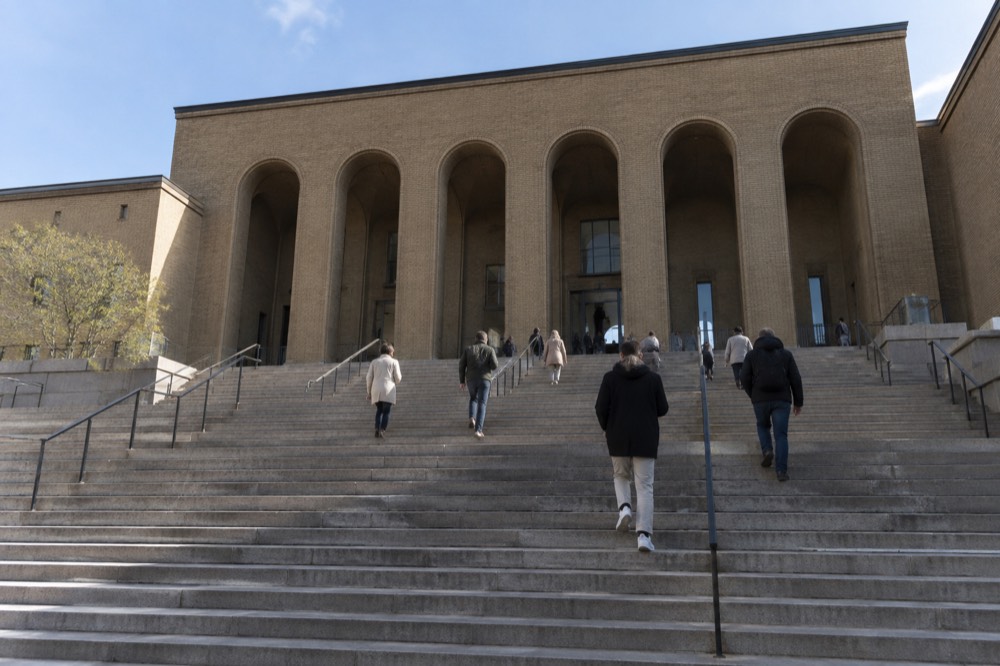 A grand staircase inside a Nordic art museum with visitors climbing toward a lit gallery