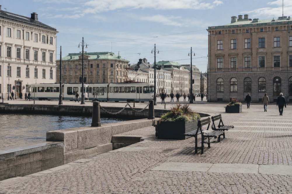 A vintage white tram on a street in Gothenburg with brick buildings behind it