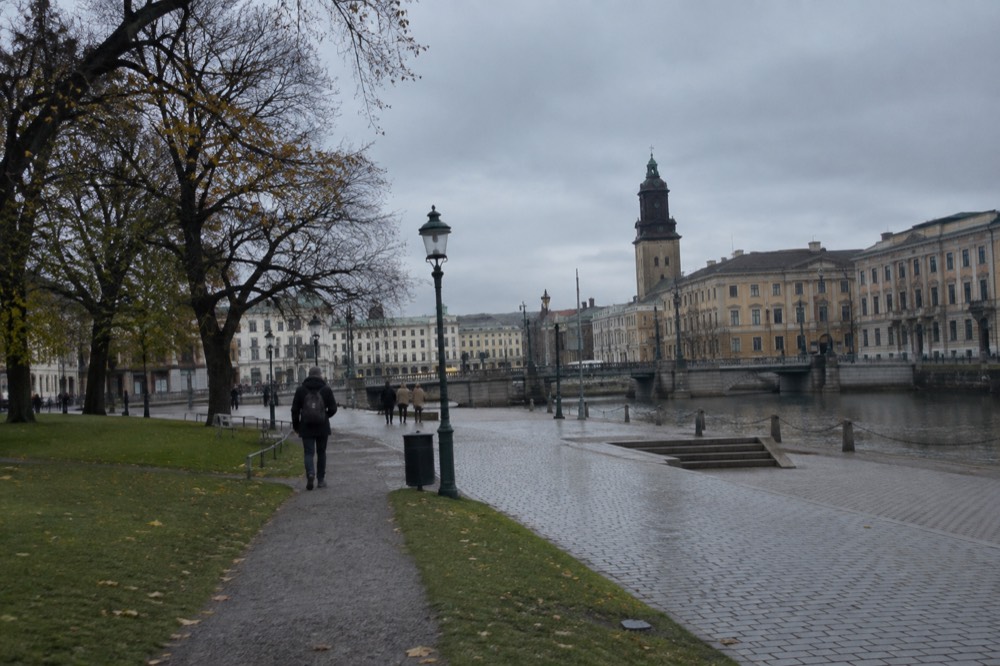 A wide green park in Gothenburg with lawns, old trees and a path leading toward the city skyline