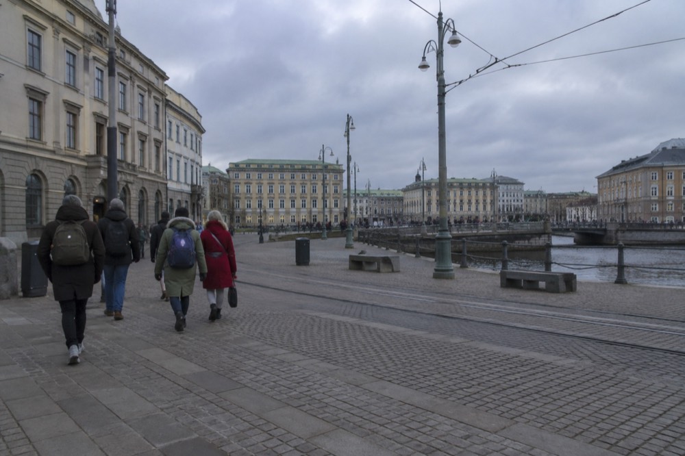 A small group of walkers following a guide down a cobblestone street of old wooden houses