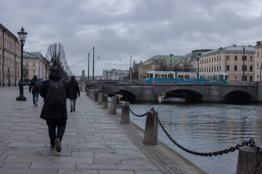 A blue Gothenburg tram crossing a stone bridge over a canal in the city centre