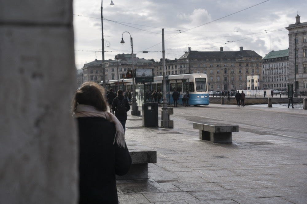 Blue Gothenburg tram arriving at a stop near a cinema district
