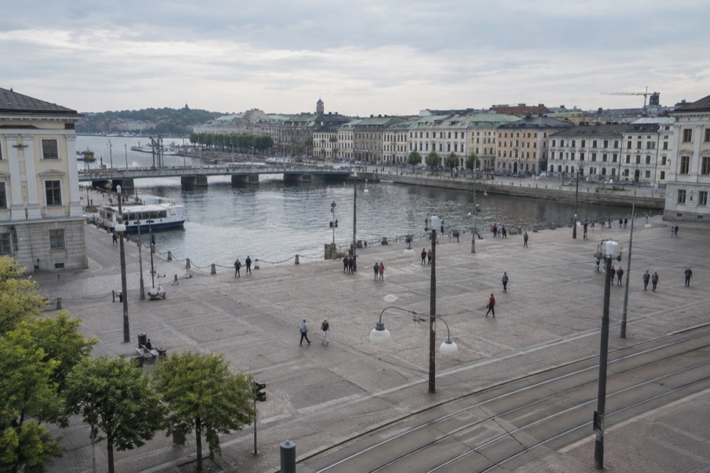 Lit harbour promenade with people walking beside dark water