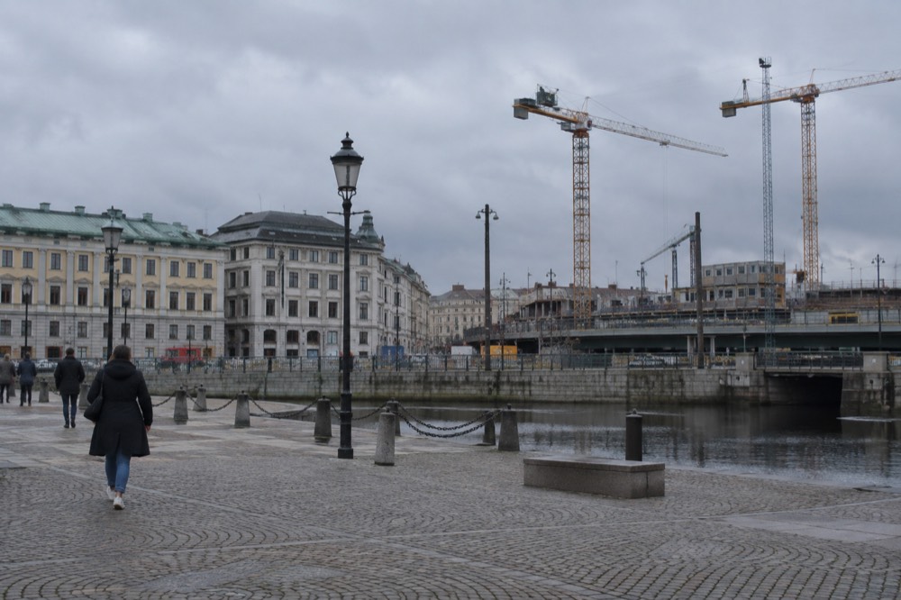 Construction cranes and fenced works beside a railway viaduct in central Gothenburg
