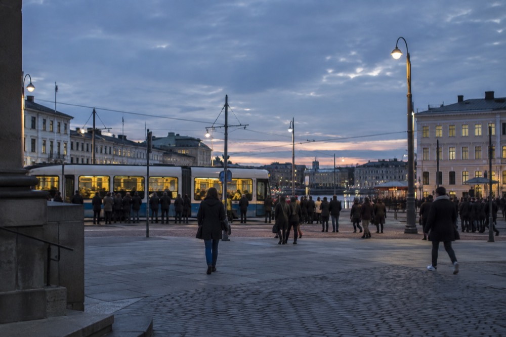 A blue Gothenburg tram moving along a street with festival crowds waiting at the stop