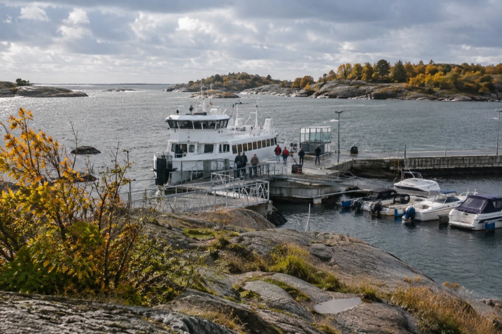 A ferry at Saltholmen pier with autumn-coloured trees on the archipelago islands beyond