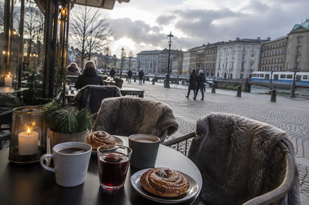 A candle-lit Swedish cafe table with coffee, cinnamon buns and glögg