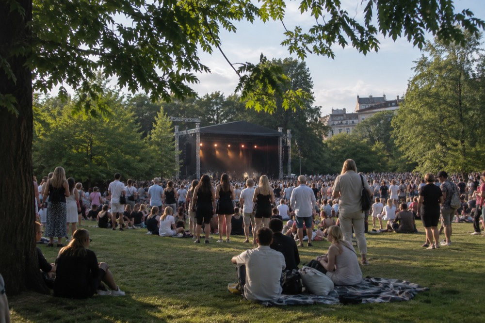 Crowd at an outdoor summer music festival in a green city park