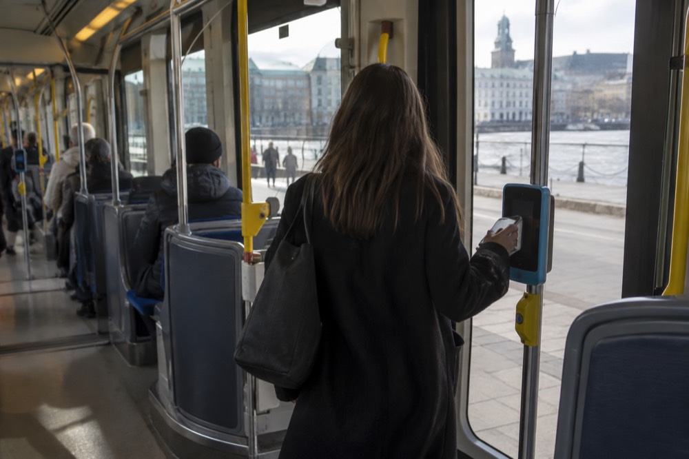 Passenger tapping a phone on a tram ticket reader inside a Gothenburg tram