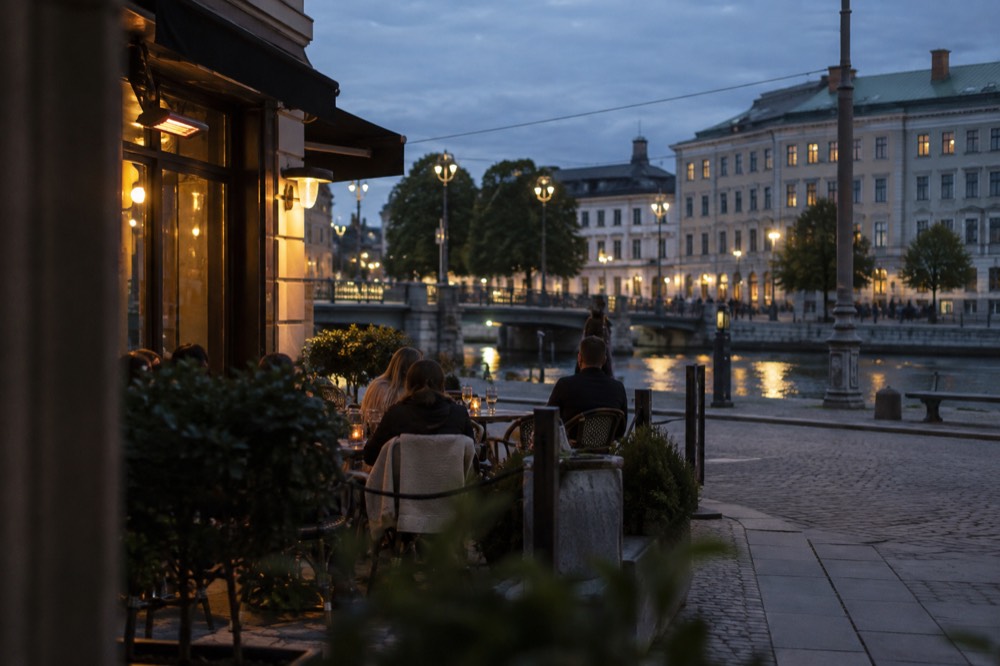 People sitting at outdoor tables outside a corner pub in Gothenburg on a summer evening