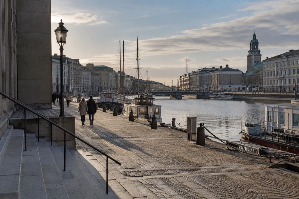 Golden evening light over a Scandinavian harbour with boats moored along the quay