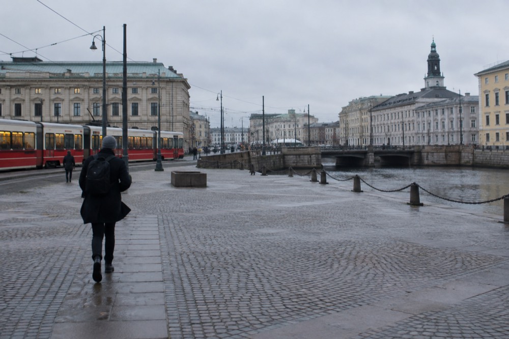 Red trams and stone buildings along a Gothenburg canal under a grey Nordic sky