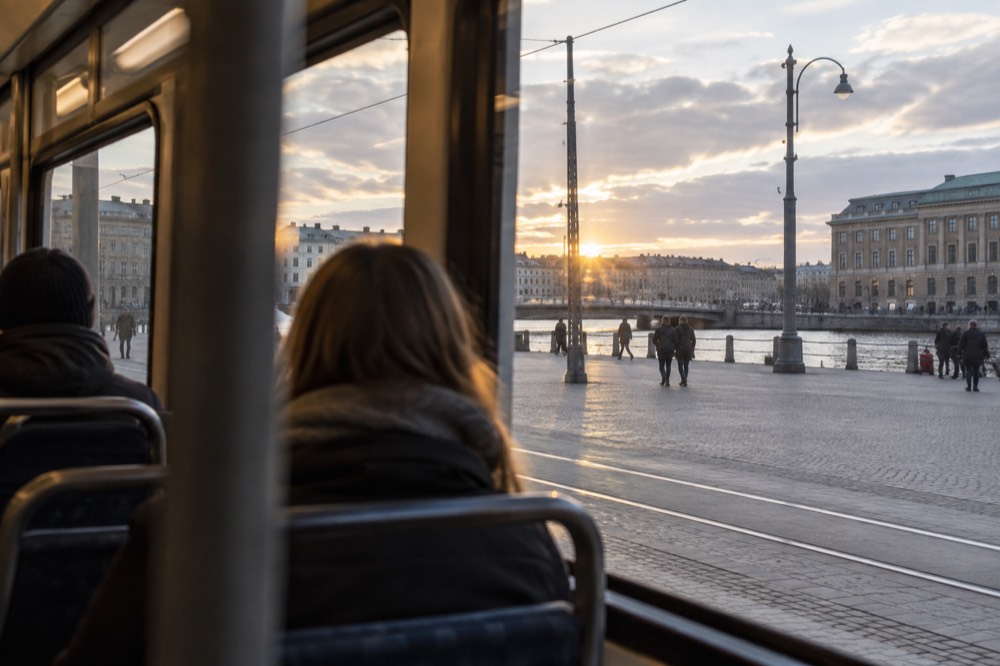 A tram interior with a few passengers and a view over the river