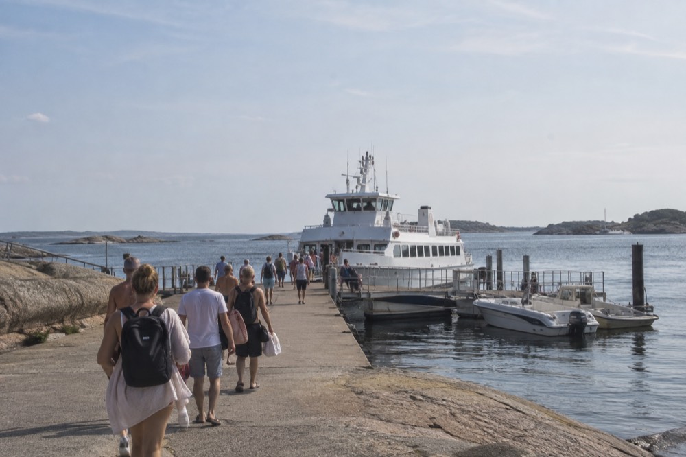 A ferry jetty at Saltholmen with bathers walking toward a moored archipelago boat in summer light