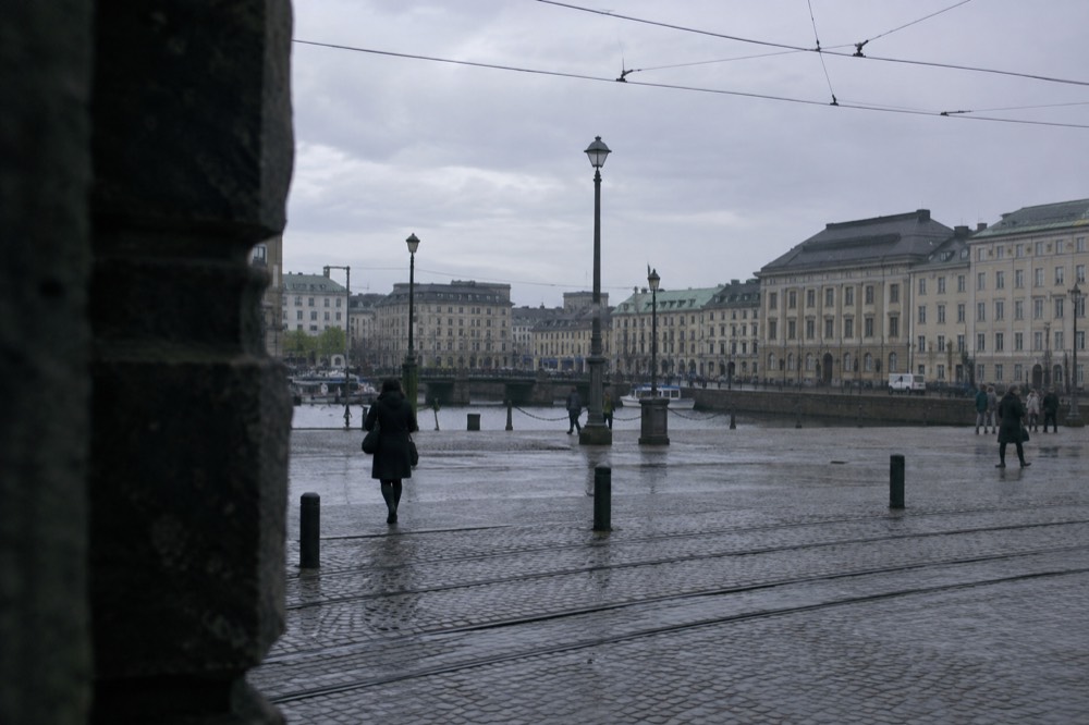 A folded towel and wooden ladle on a sauna bench beside a hot stone stove