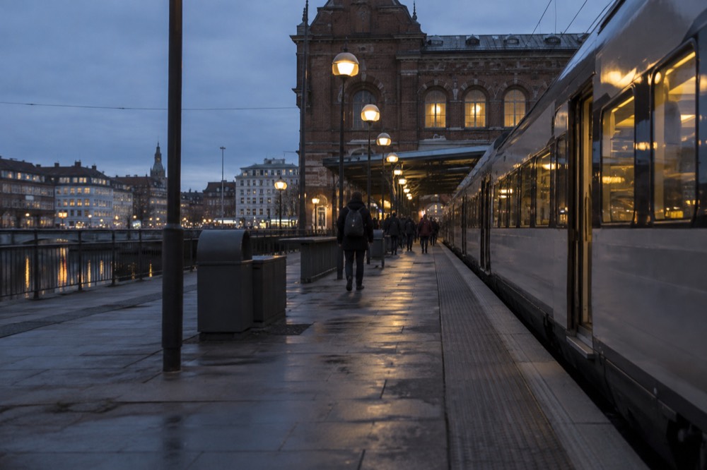 A passenger train standing at a platform beside a brick station building in Gothenburg, Sweden