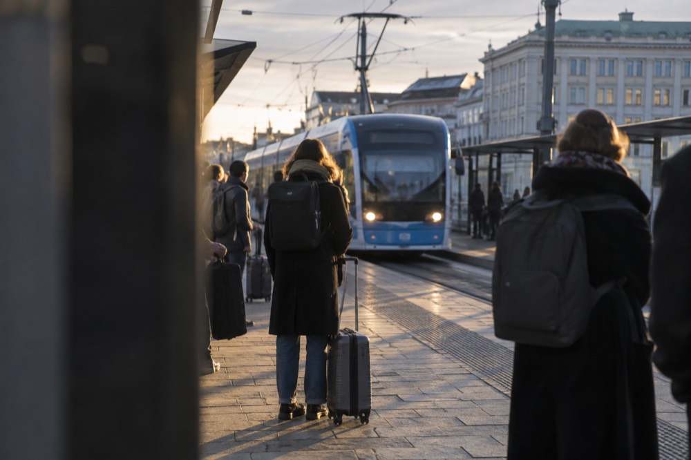 Passengers waiting with luggage on a station platform as a regional train arrives