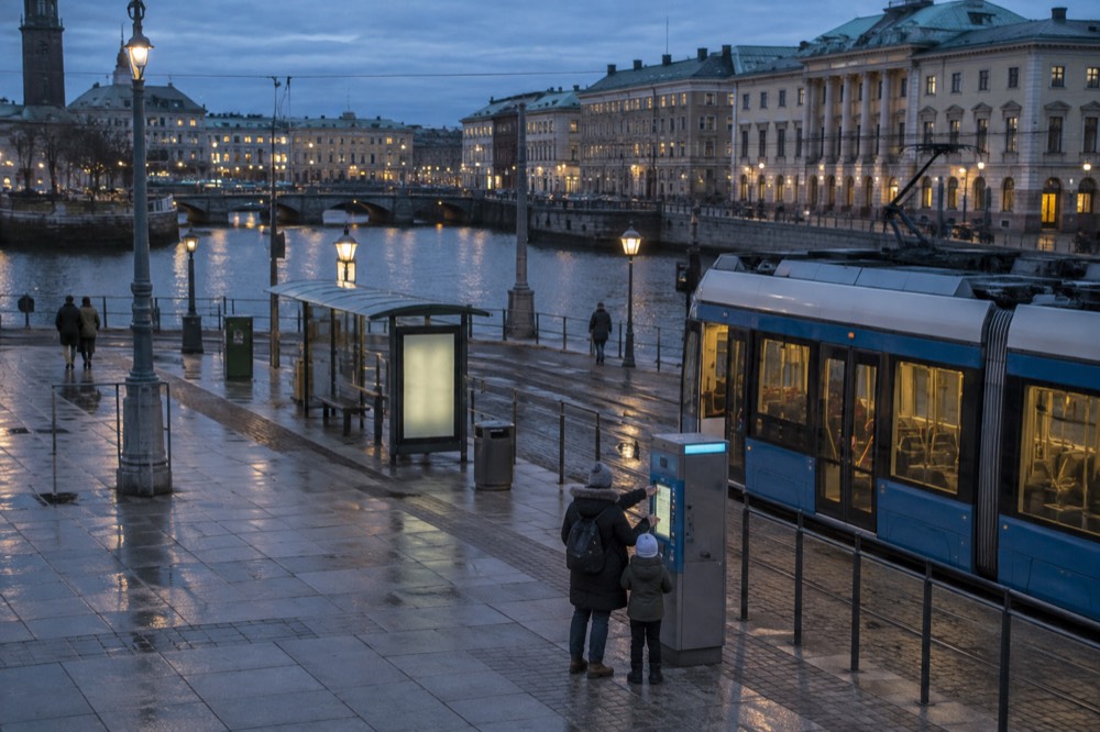 A parent buying tram tickets from a machine at a Gothenburg platform