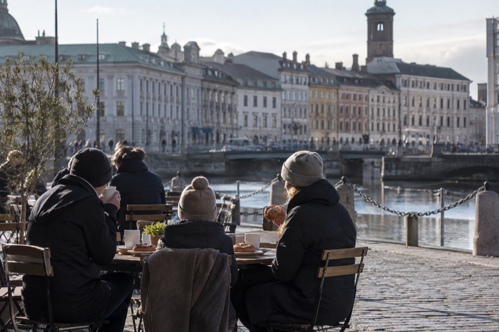 A family sharing cinnamon buns and coffee at a wooden table in a Swedish cafe