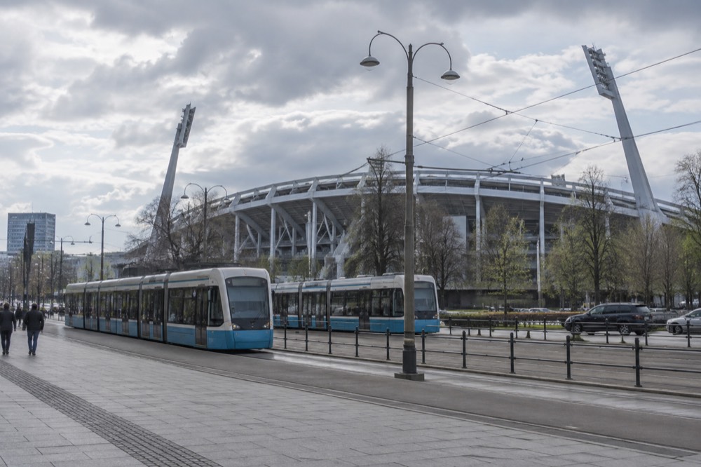 A wide view of Gothenburg's Ullevi stadium area under grey Scandinavian sky with trams passing on the avenue outside