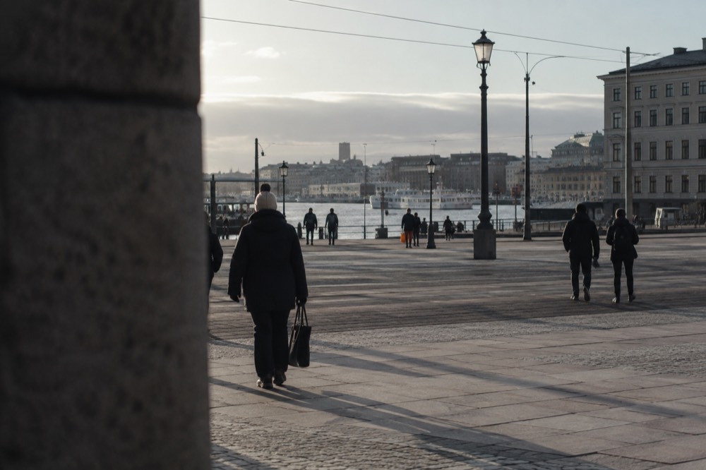 Walkers in windproof jackets on a granite hilltop path above Gothenburg harbour