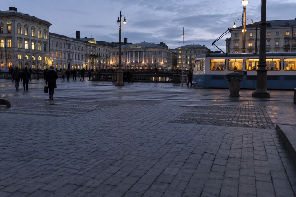 An amusement park entrance plaza with a turnstile and ticket scanners in evening light