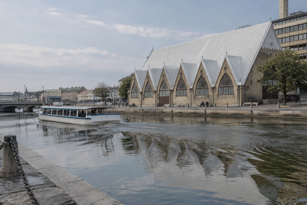 A canal boat passing the timbered fish market hall Feskekôrka in Gothenburg