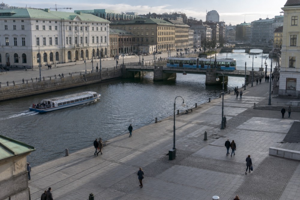 A tour boat and a tram crossing the same canal intersection in Gothenburg