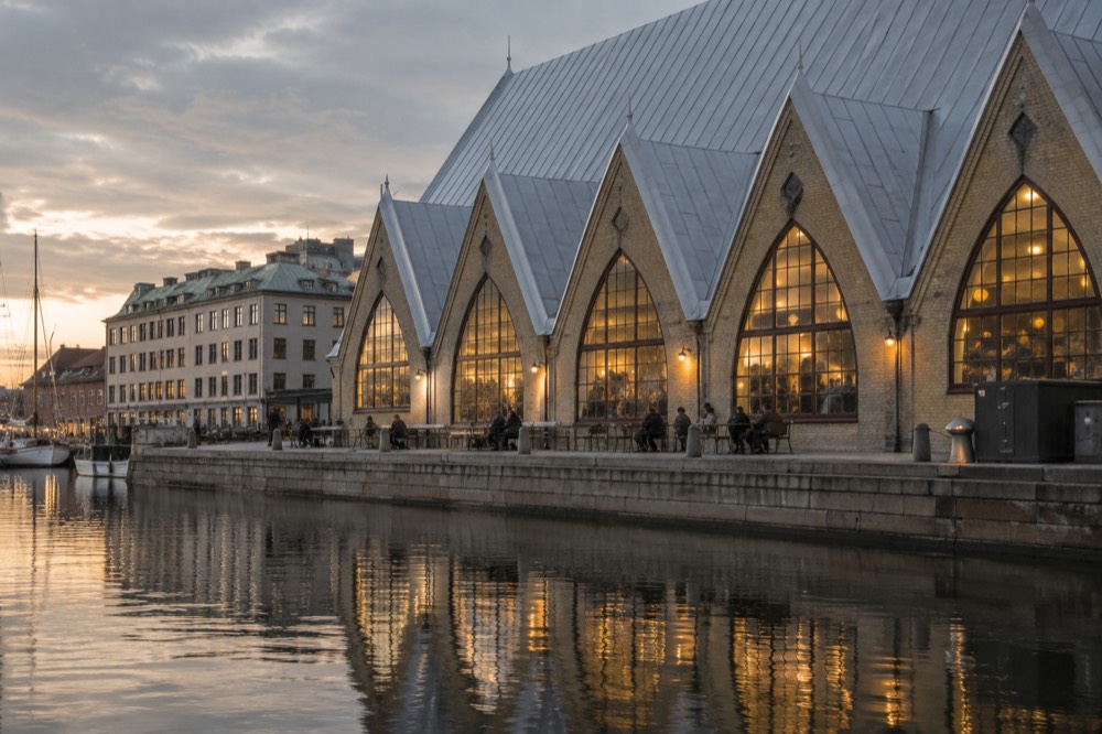 The timber interior of Feskekorka fish hall in Gothenburg with a fish counter and diners at small tables