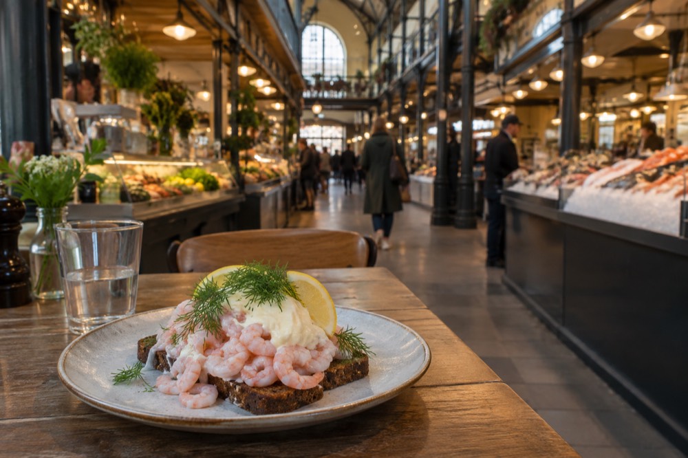 An open shrimp sandwich with mayonnaise, dill and lemon on dark bread on a wooden table