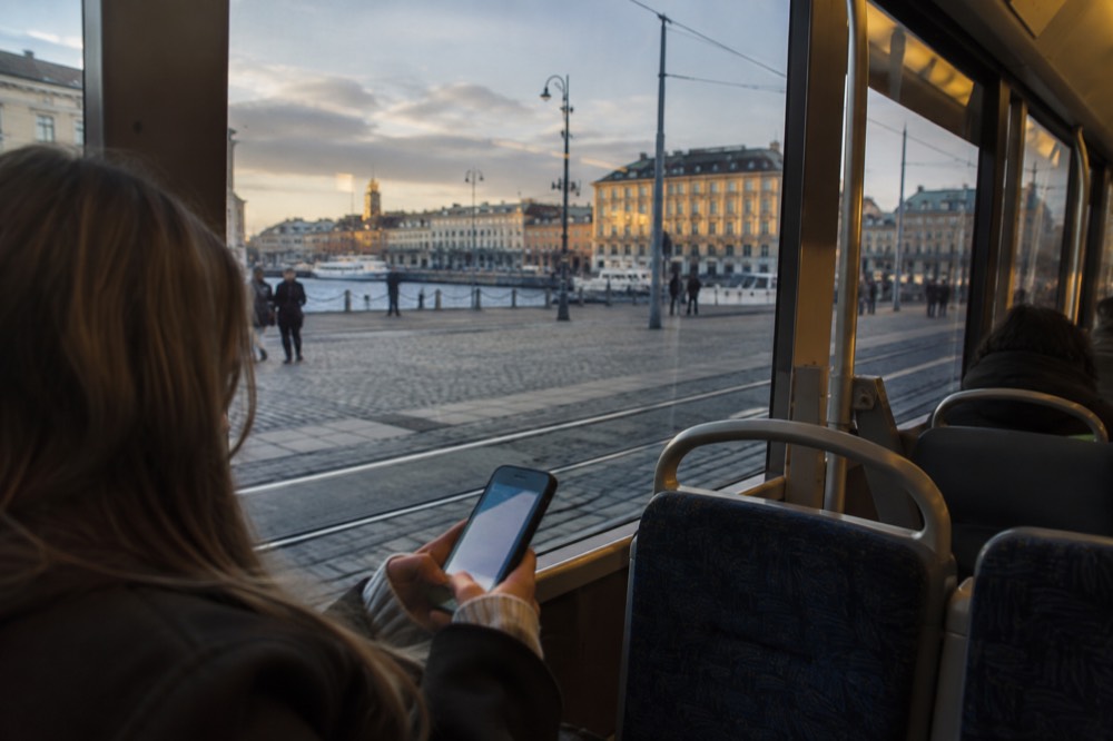 A commuter holding a phone showing a tram ticket app inside a Gothenburg tram