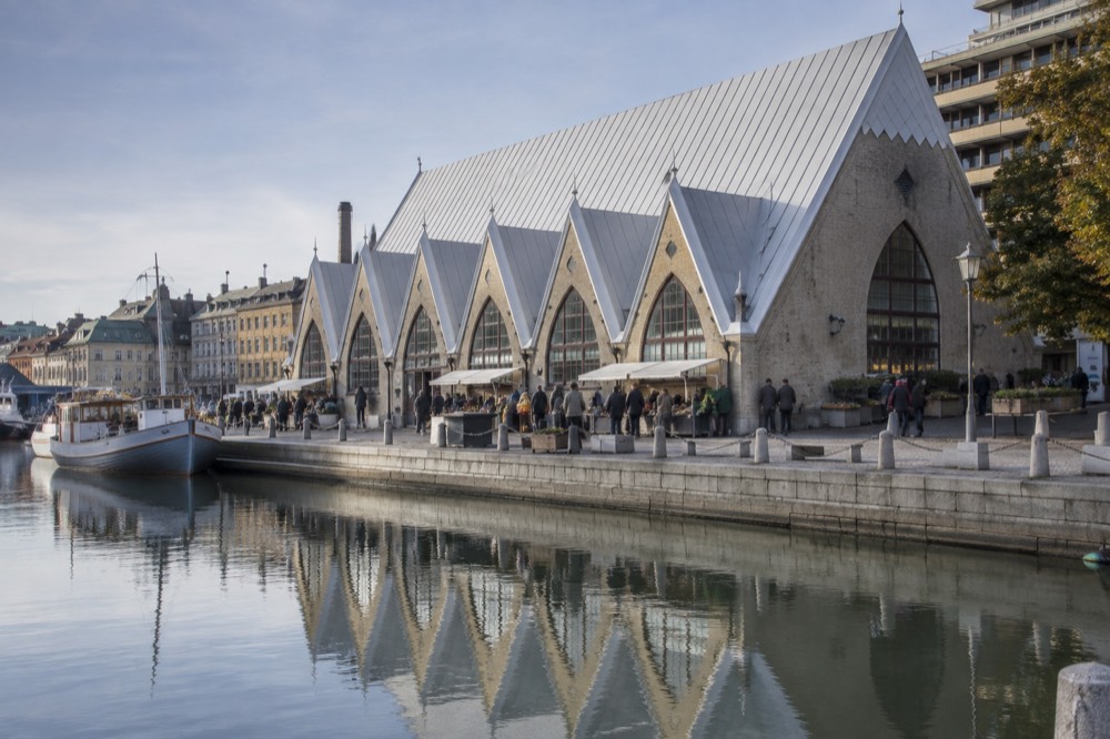 The wooden interior of the Feskekôrka food hall in Gothenburg with food stalls and visitors