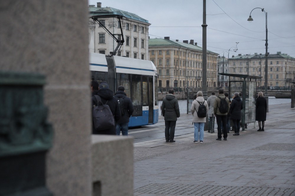 Commuters waiting in an orderly line at a tram stop in Gothenburg