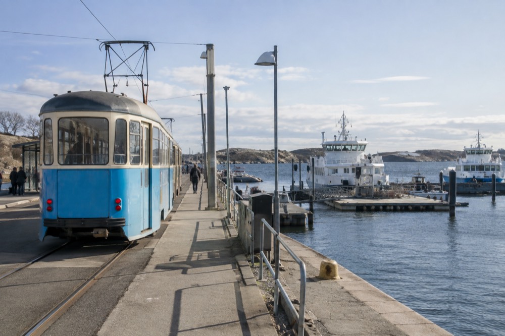 A vintage-style Gothenburg tram at the Saltholmen terminus beside the water, ferry jetty beyond
