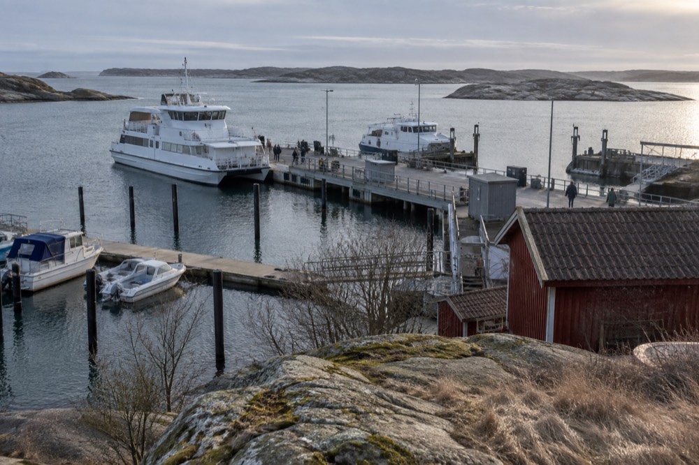 Low winter sun lighting granite shoreline and weathered wooden boathouses on a Gothenburg archipelago island