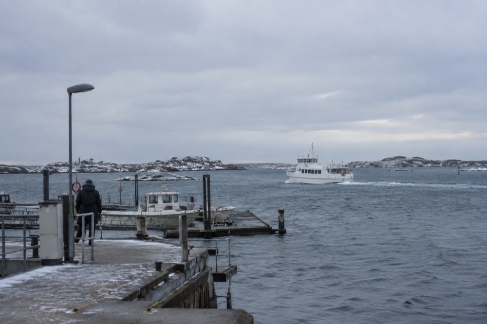 A white archipelago ferry crossing grey open water toward snow-flecked islands