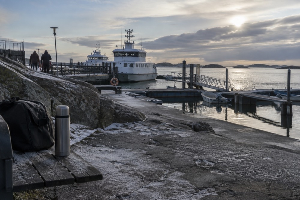A thermos and packed bag on a wooden bench beside a frost-covered jetty