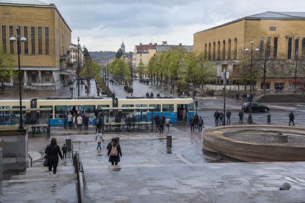A Gothenburg tram at street level with passengers boarding at a stop near the stadium district