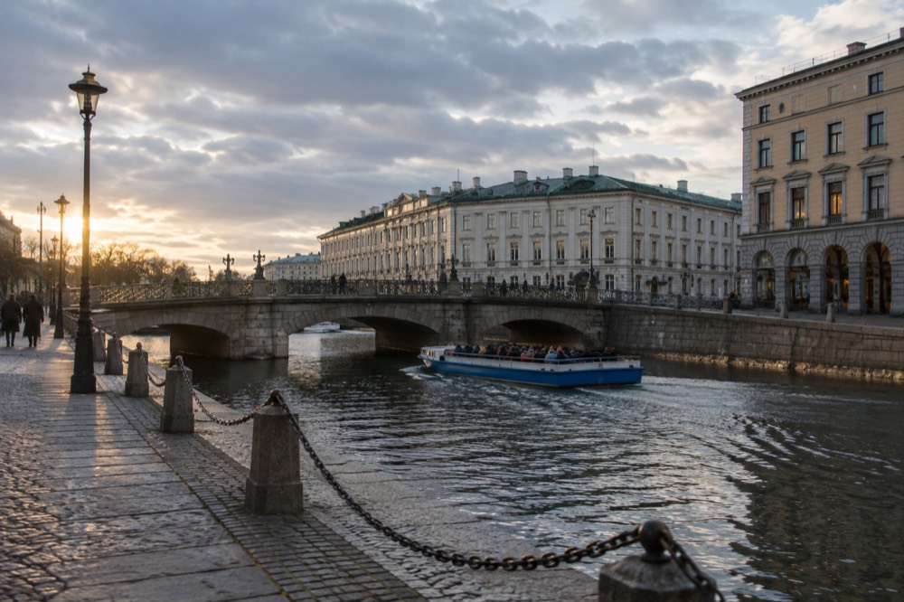 A Paddan sightseeing boat passing under a low canal bridge in central Gothenburg